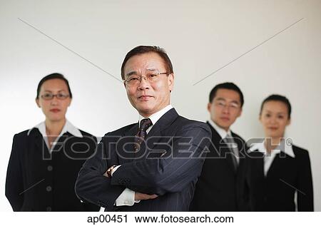 Businessman with arms crossed, people in the background View Large Photo Image Stock Image - Businessman with arms crossed, people in the background. Fotosearch