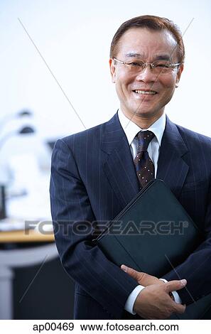 Stock Photo - Businessman with binder, looking at camera, portrait. Fotosearch