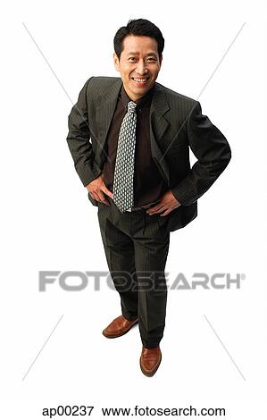 Stock Photo - Businessman with hands on hips, smiling at camera. Fotosearch