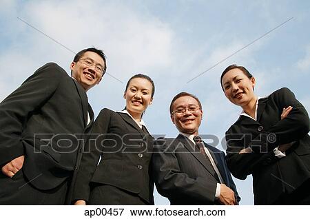 Stock Photo - Businessmen and businesswomen looking down at camera, smiling. Fotosearch