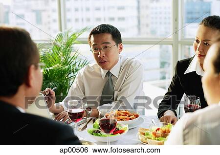 Stock Photograph - Businessmen and women, talking over lunch. Fotosearch