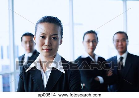 Businesswoman looking at camera, people in the background View Large Photo Image Picture - Businesswoman looking at camera, people in the background. Fotosearch