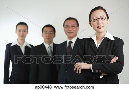 Businesswoman with arms crossed, other executives in the background View Large Photo Image Stock Photo - Businesswoman with arms crossed, other executives in the background. Fotosearch
