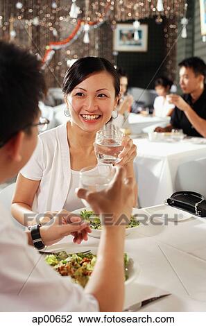Couple at restaurant, holding glasses of water, over the shoulder view View Large Photo Image Stock Image - Couple at restaurant, holding glasses of water, over the shoulder view. Fotosearch