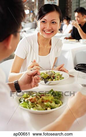 Stock Image - Couple eating at restaurant, over the shoulder view. Fotosearch
