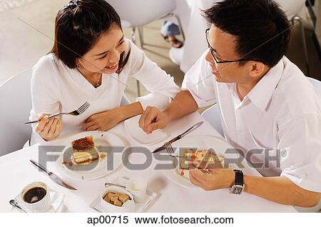 Couple eating dessert in restaurant, high angle view View Large Photo Image Stock Photography - Couple eating dessert in restaurant, high angle view. Fotosearch
