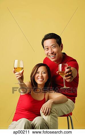 Couple holding drinks up for a toast View Large Photo Image Stock Image - Couple holding drinks up for a toast. Fotosearch