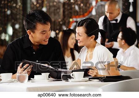 Couple in restaurant, holding menu and smiling at each other View Large Photo Image Stock Image - Couple in restaurant, holding menu and smiling at each other. Fotosearch