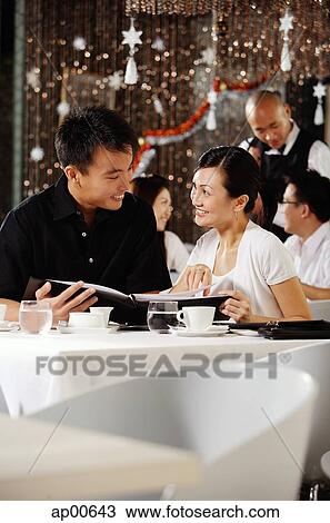 Couple in restaurant, holding menu, smiling at each other View Large Photo Image Stock Image - Couple in restaurant, holding menu, smiling at each other. Fotosearch