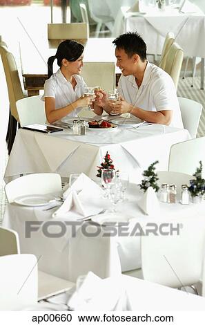 Stock Image - Couple in restaurant, looking at each other. Fotosearch