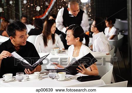 Stock Photo - Couple in restaurant, looking at menus. Fotosearch