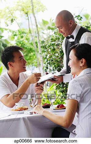Stock Photograph - Couple in restaurant, making payment to waiter. Fotosearch