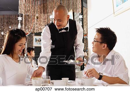 Couple in restaurant, waiter serving plates of dessert View Large Photo Image Stock Photo - Couple in restaurant, waiter serving plates of dessert. Fotosearch