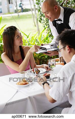 Couple in restaurant, woman giving credit card to waiter View Large Photo Image Stock Image - Couple in restaurant, woman giving credit card to waiter. Fotosearch