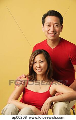 Stock Photo - Couple sitting, looking at camera. Fotosearch