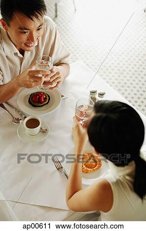 Stock Image - Couple sitting opposite each other at cafe, high angle view. Fotosearch