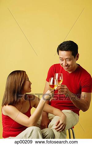 Stock Photo - Couple sitting, toasting with drinks. Fotosearch