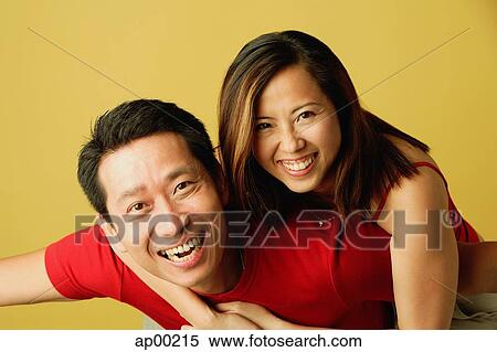 Couple smiling at camera, woman hugging man from behind View Large Photo Image Stock Photography - Couple smiling at camera, woman hugging man from behind. Fotosearch