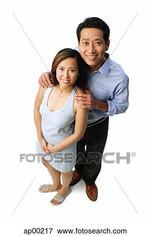 Stock Photo - Couple standing side by side, smiling at camera. Fotosearch