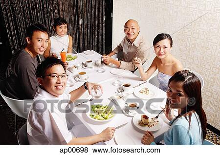 Stock Photo - Couples at dining table, looking at camera. Fotosearch