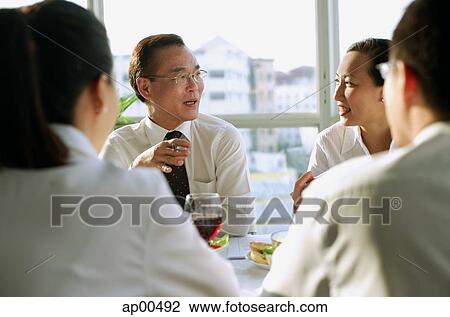 Stock Image - Executives discussing over lunch. Fotosearch