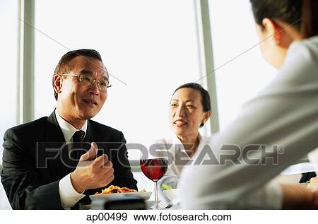 Stock Photo - Executives having lunch meeting, low angle view. Fotosearch