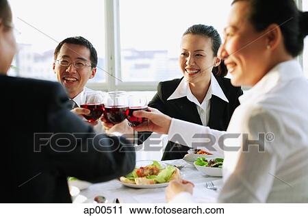 Stock Image - Executives holding wine glasses and toasting. Fotosearch