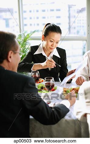 Stock Image - Executives looking at documents over lunch. Fotosearch