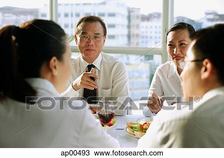 Stock Image - Executives meeting over lunch. Fotosearch