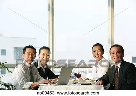Executives sitting at lunch table, smiling at camera View Large Photo Image Stock Image - Executives sitting at lunch table, smiling at camera. Fotosearch