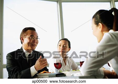 Stock Image - Executives talking over lunch. Fotosearch