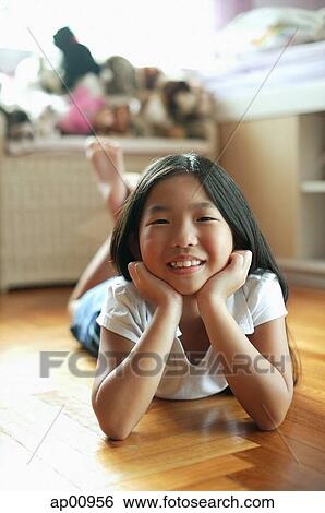 Girl in bedroom, lying on floor, hands on chin, looking at camera View Large Photo Image Stock Photograph - Girl in bedroom, lying on floor, hands on chin, looking at camera. Fotosearch