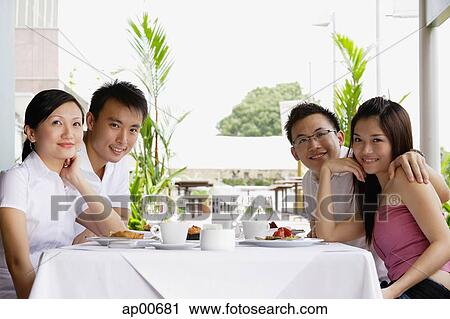 Group of friends at restaurant table, some looking a camera View Large Photo Image Stock Image - Group of friends at restaurant table, some looking a camera. Fotosearch