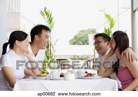 Group of friends at restaurant table, laughing View Large Photo Image Stock Image - Group of friends at restaurant table, laughing. Fotosearch