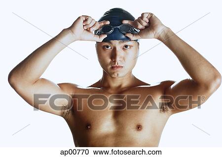 Stock Image - Man adjusting swimming goggles, looking at camera, portrait. Fotosearch