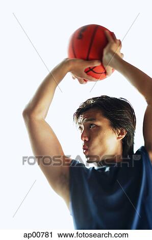 Stock Image - Man aiming basketball, concentrating. Fotosearch