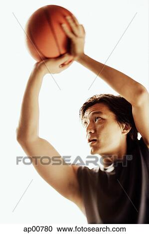 Stock Image - Man aiming basketball, looking away. Fotosearch