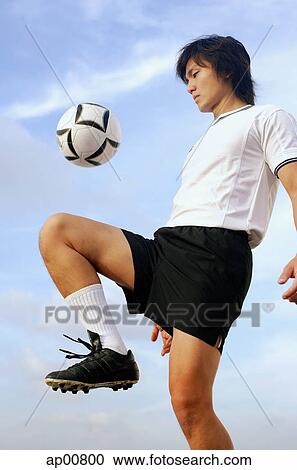 Stock Image - Man bouncing soccer ball on knee. Fotosearch