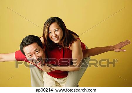 Man carrying woman on back, arms outstretched View Large Photo Image Picture - Man carrying woman on back, arms outstretched. Fotosearch