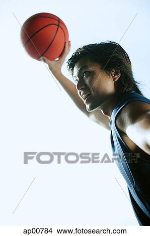 Man holding basketball in the air, smiling View Large Photo Image Picture - Man holding basketball in the air, smiling. Fotosearch