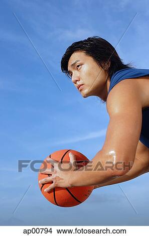 Picture - Man holding basketball, side view. Fotosearch