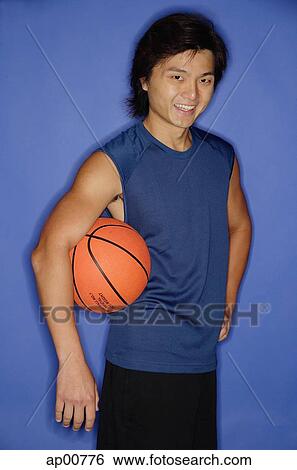 Man holding basketball under arm, looking at camera, smiling View Large Photo Image Stock Photograph - Man holding basketball under arm, looking at camera, smiling. Fotosearch