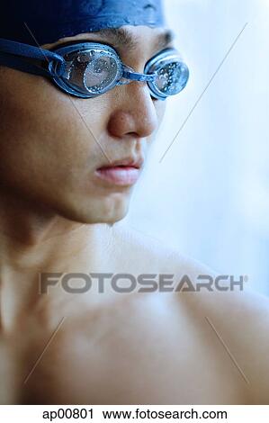 Stock Image - Man in swimming cap and goggles, looking away, portrait. Fotosearch