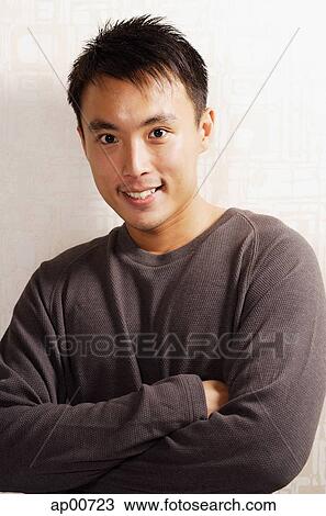 Stock Image - Man looking at camera, arms crossed, portrait. Fotosearch