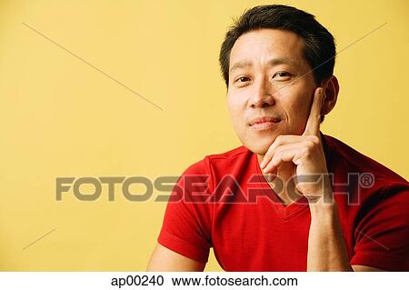 Stock Image - Man looking at camera, hand on chin. Fotosearch
