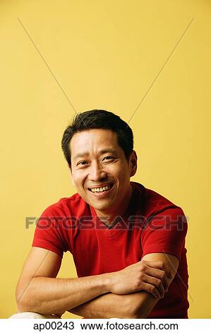 Stock Image - Man smiling at camera, arms crossed, portrait. Fotosearch