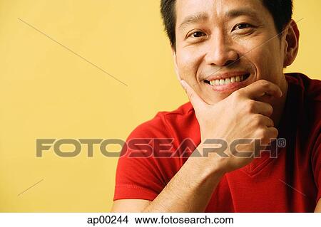 Picture - Man smiling at camera, hand on chin. Fotosearch