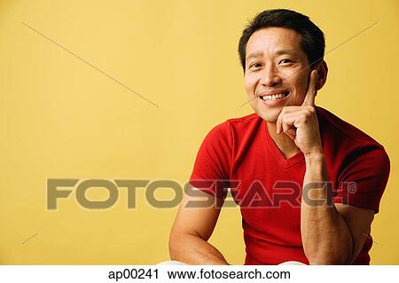 Stock Image - Man smiling at camera, hand on chin. Fotosearch