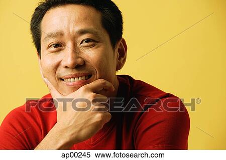 Stock Photography - Man smiling at camera, hand on chin, portrait. Fotosearch