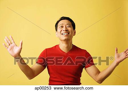 Stock Image - Man smiling, looking up, arms outstretched. Fotosearch